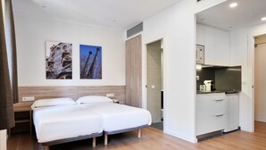 Una habitación de hotel con una cama, una kitchenette y dos obras de arte colgadas en la pared.