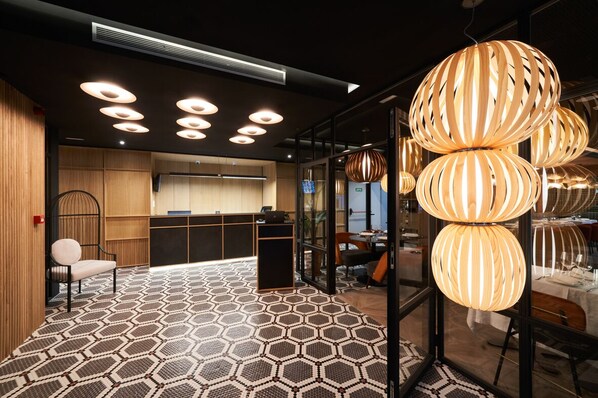 A modern hotel lobby with a geometric patterned floor, a reception desk, and contemporary pendant lighting. - Aparthotel Augusta Barcelona (Barcelona)