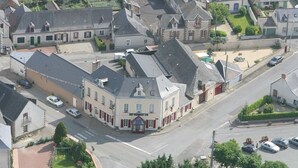Vue aérienne d’un bâtiment historique doté d’une cour intérieure, entouré d’immeubles résidentiels et bordé par une rue principale.