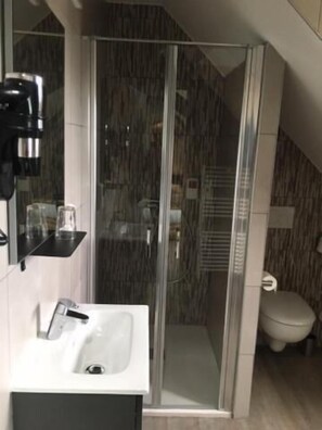 Une salle de bain moderne avec une douche à parois de verre, un lavabo et des toilettes.