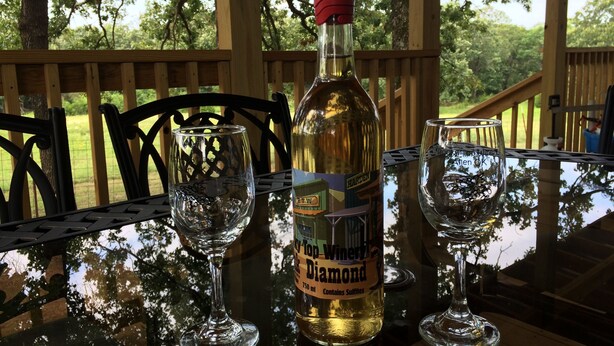 Een fles Diamond-wijn op een tafel met twee lege glazen.