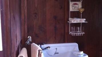 A wooden interior with a white sink, a towel rack, and a small shelf with decorative items.