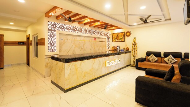 A reception area with a marble counter, a sofa, and a ceiling fan. - Hotel NNP Grand (Rameshwaram)