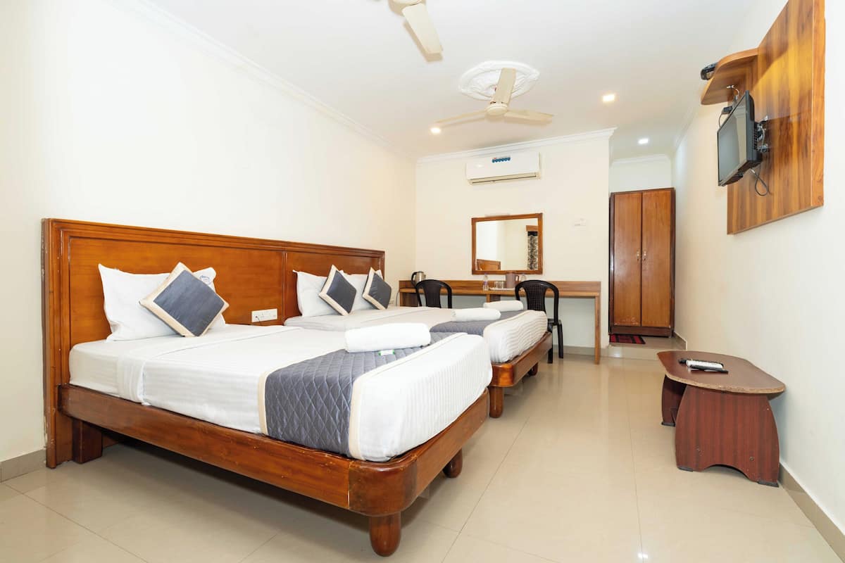 A hotel room with a wooden bed, a desk, a chair, a TV mounted on the wall, and a wardrobe.