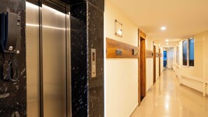 A modern elevator with a marble wall, a phone, and a digital display. - Hotel NNP Grand (Rameshwaram)
