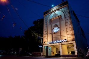 Un bâtiment d'hôtel avec une enseigne bien visible indiquant « HÔTEL NNP GRAND » et une entrée décorée avec goût.