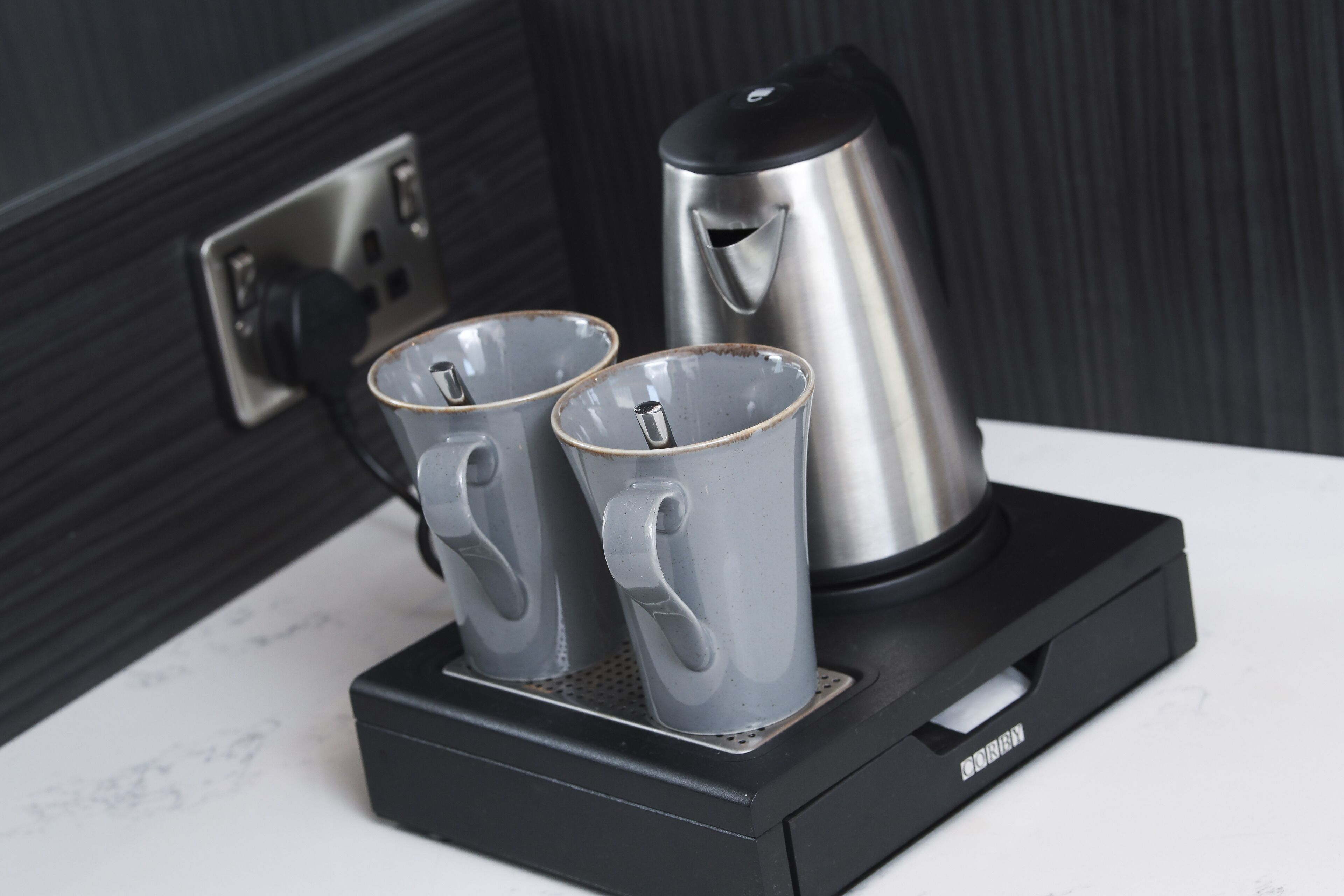 A coffee maker with two cups on a black stand.