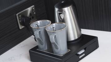 A coffee maker with two cups on a black stand.