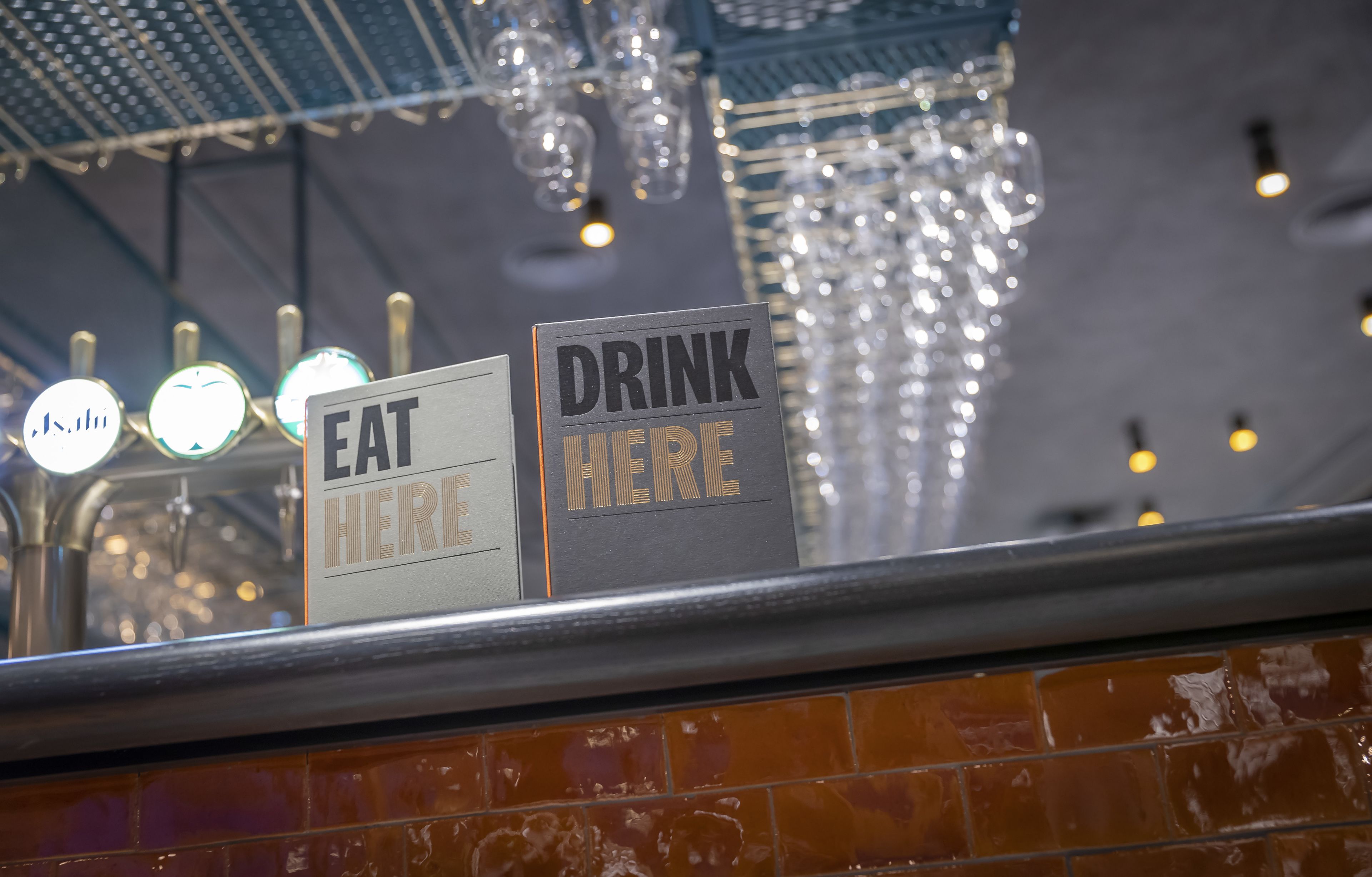 Un cartel con las palabras 'DRINK HERE' y 'EAT HERE' que indica una zona dentro de un restaurante o bar.