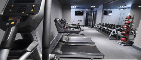 Un gimnasio con cintas de correr, elípticas y una variedad de pesas.