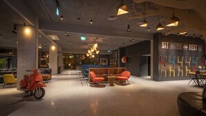 A modern interior with seating areas, a motorcycle, and a wall with illuminated letters. - Marlin Hotel Stephens Green (Dublin)