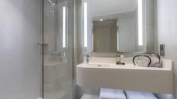 A modern bathroom with a glass-enclosed shower, a white sink, and a large mirror.