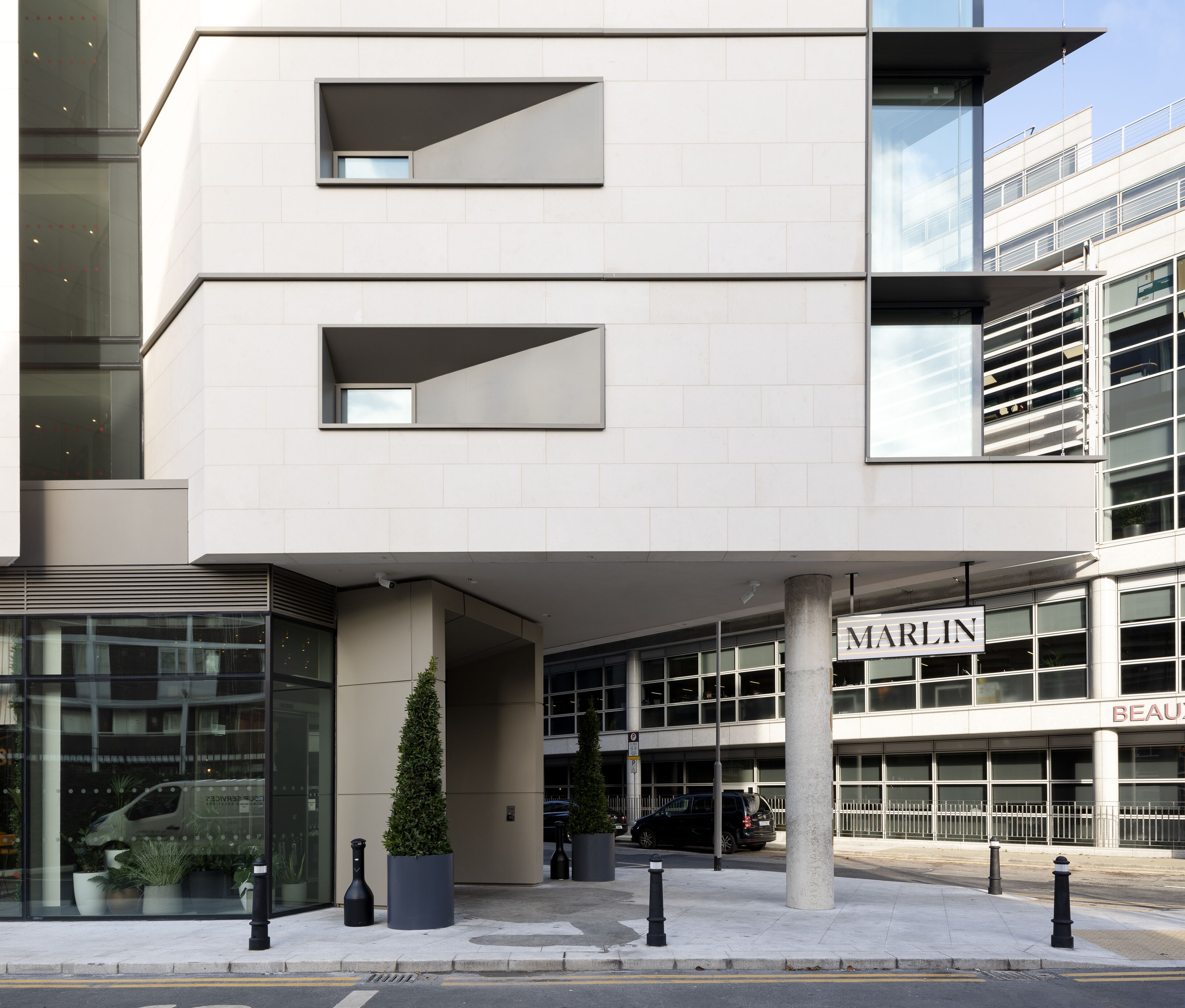 A modern building with a glass facade, a visible entrance, and a sign that reads "MARLIN".