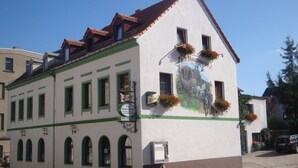 A building with a green and white facade, multiple windows, and a sign indicating it is a pension. - Pension Zum Bauernstübl (Meerane)