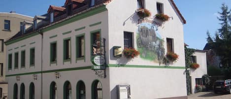 A building with a green and white facade, multiple windows, and a sign indicating it is a pension.