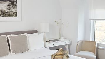 Ein Schlafzimmer mit einem Bett, Nachttisch, Lampe, einer Vase mit Trockenpflanzen und einem Sessel.
