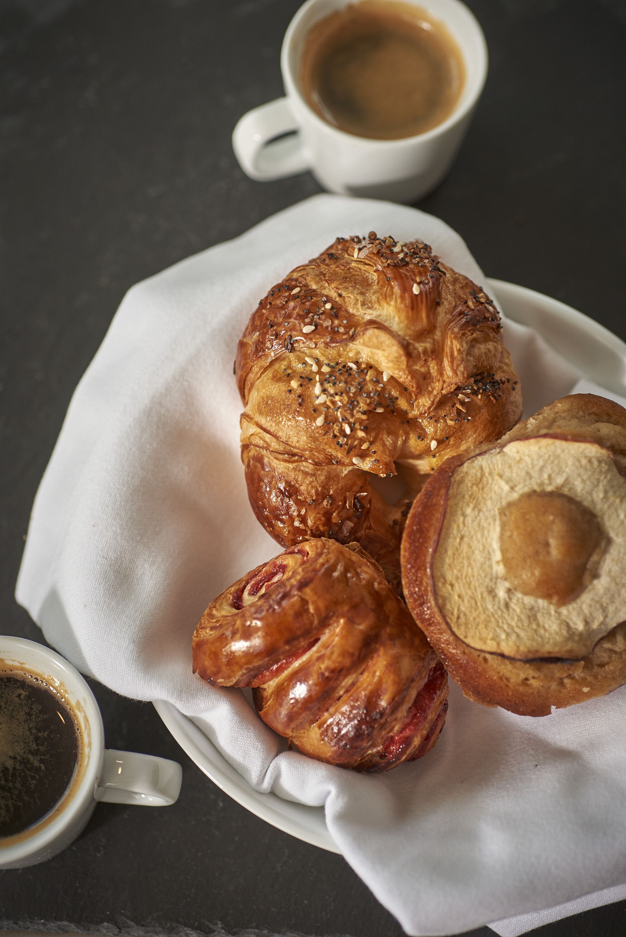 A plate with pastries and a cup of coffee on a dark surface.