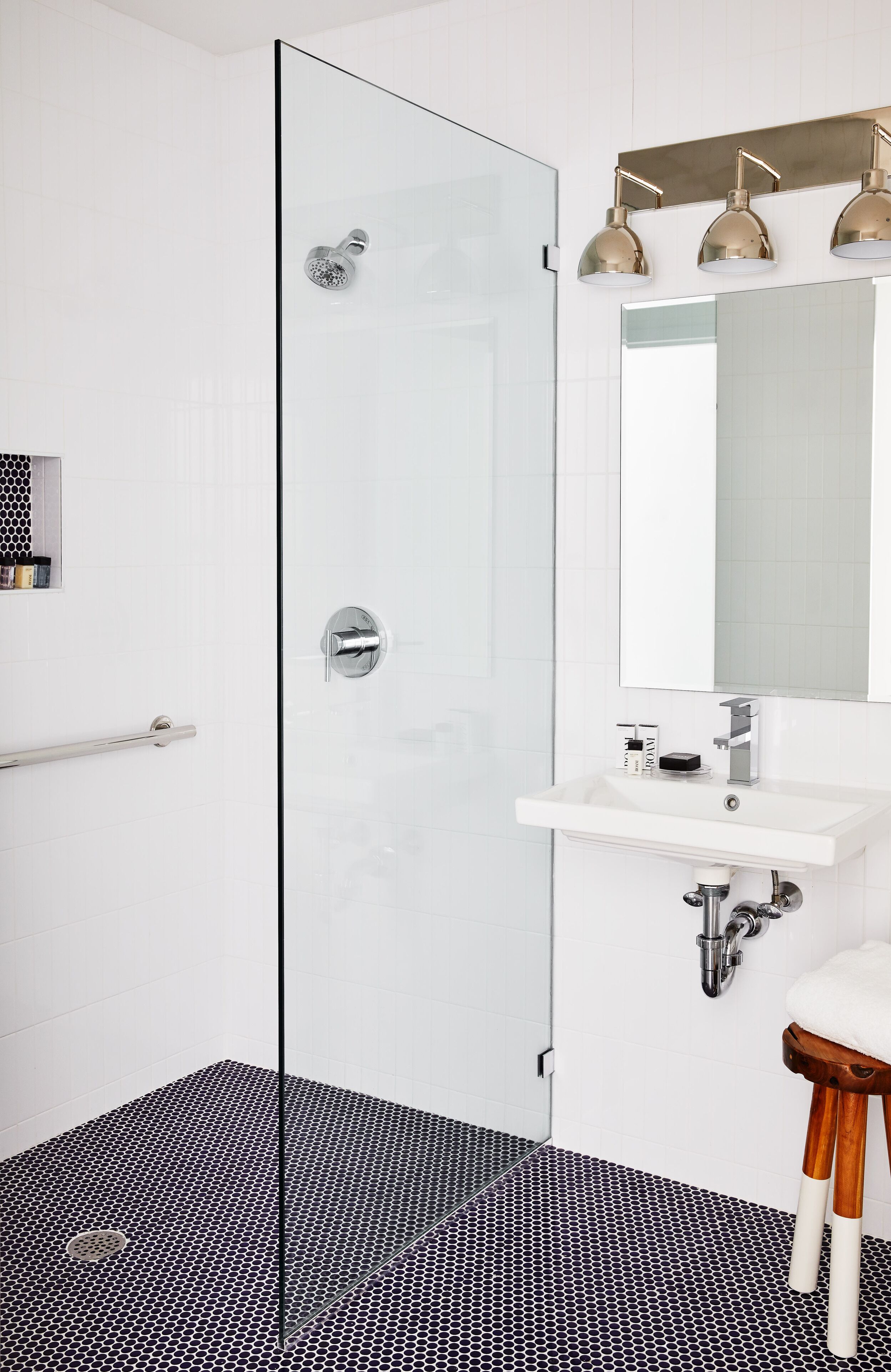 Ein modernes Badezimmer mit Duschkabine aus Glas, einem weißen Waschbecken und einem großen Spiegel.