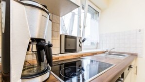 A modern kitchen with a coffee maker, microwave, and induction cooktop. - Tripcologne Apartments since 2013 (Cologne)