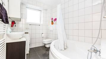 Ein modernes Badezimmer mit Badewanne, Toilette und Waschbecken.