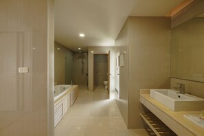 A modern bathroom with a large bathtub, a sink, and a shower area. - Jolly Suites Petkasem (Krathum Baen)