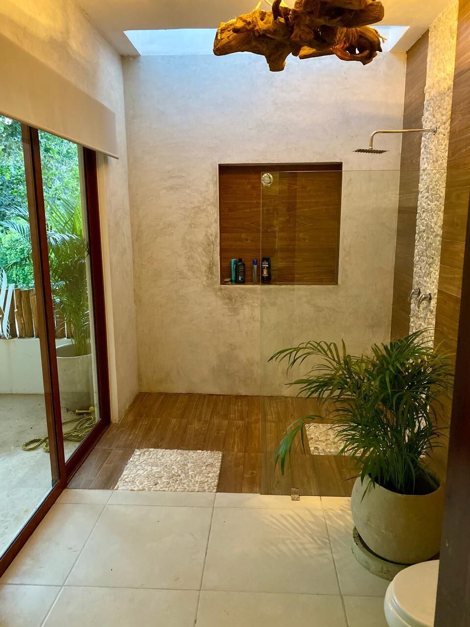 Un baño moderno con tocador de madera, ducha y una planta en maceta.