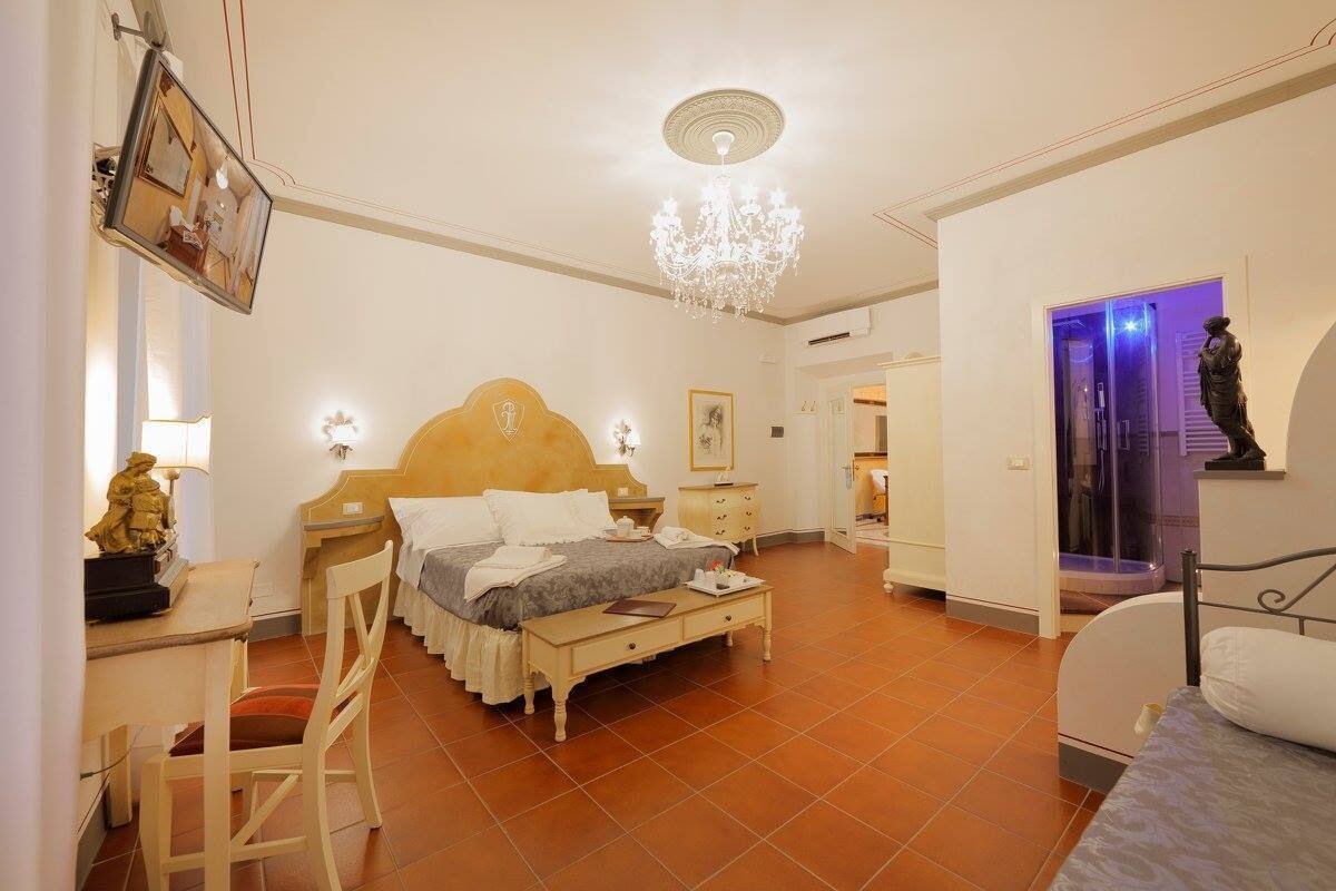 Een slaapkamer met een bed, nachtkastjes, een bureau, een stoel en een kroonluchter.