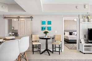 Een moderne woonkamer met een eethoek, met een centrale tafel met stoelen, een zithoek en kunst aan de muur.
