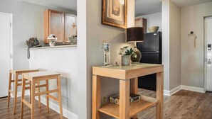 Una cocina moderna con armarios de madera, un refrigerador negro y una zona de comedor con una mesa y sillas de madera.