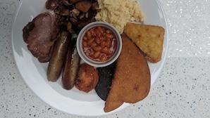 A plate of food including sausages, mushrooms, scrambled eggs, baked beans, and a fried item. - Lion House Bed and Breakfast (Ilfracombe)