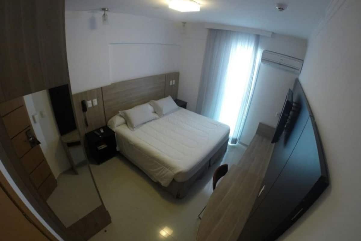 Una habitación de hotel con cama, mesita de noche y televisión.