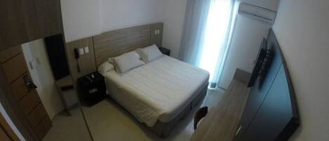 A hotel room with a bed, bedside table, and a TV.
