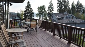 A wooden deck with outdoor furniture, a railing, and a view of houses and trees. - Mountain Harbor #137 3 Bedroom Condo (Whitefish)