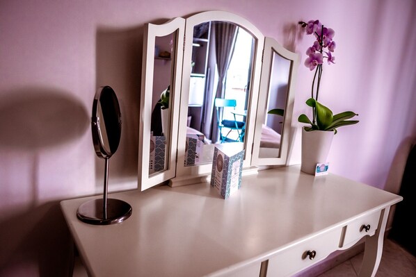 A white dresser with a mirror, a potted orchid, and a small box.