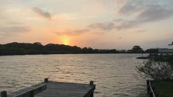 A wooden dock extending into calm water with a sunset in the background.