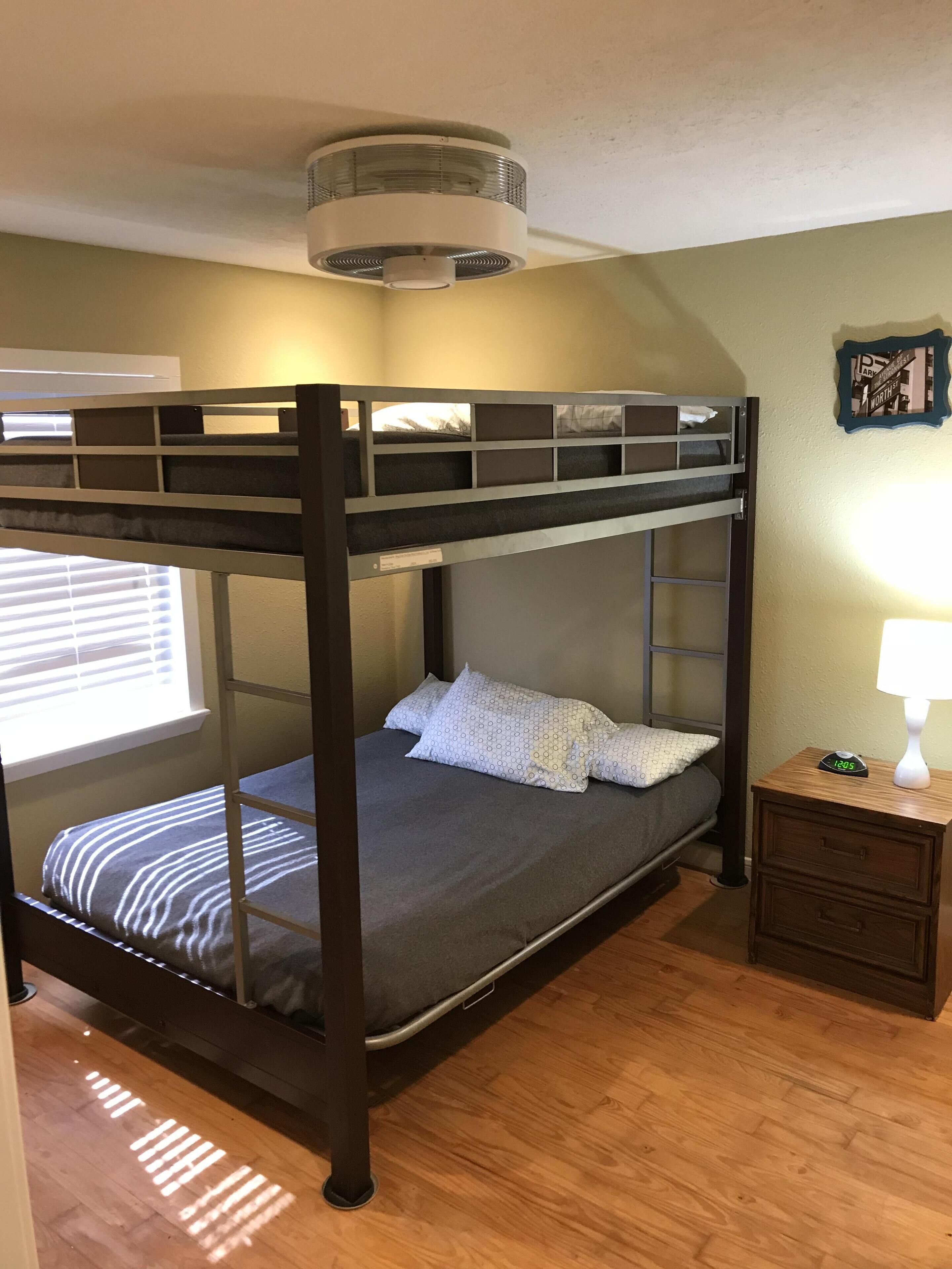 A bunk bed with a headboard, a bedside table with a lamp, and a wall clock.