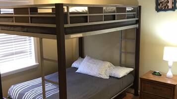 A bunk bed with a headboard, a bedside table with a lamp, and a wall clock.