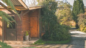 A rustic wooden cabin with a wooden door and a small porch. - Silvestre Cabanas (Puerto Varas)