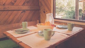 A wooden dining table with a pitcher, plates, and green cups. - Silvestre Cabanas (Puerto Varas)