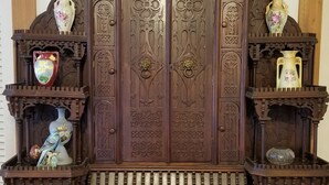 A large, ornate wooden cabinet with intricate carvings and multiple shelves.