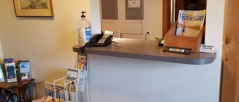 A reception desk with a phone, a bottle of hand sanitizer, a visitors' guide, and a sign for Roamike Island Taxi.
