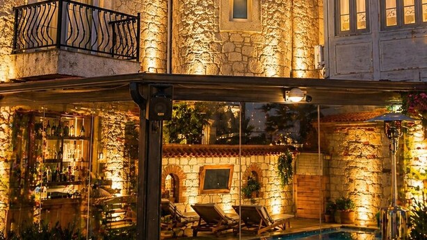 A stone building with a pool, outdoor seating, and a bar area.