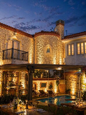 Un edificio de piedra con piscina, mobiliario exterior y zona de bar.