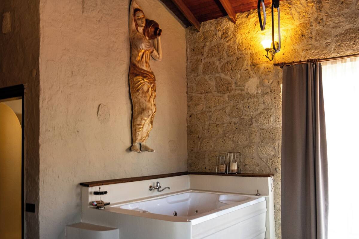 Ein Badezimmer mit einer großen Badewanne, einer Steinwand und einer Holzbalkendecke.