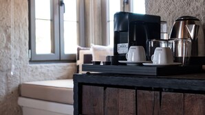 A kitchen with a coffee maker, cups, and a kettle on a wooden counter.