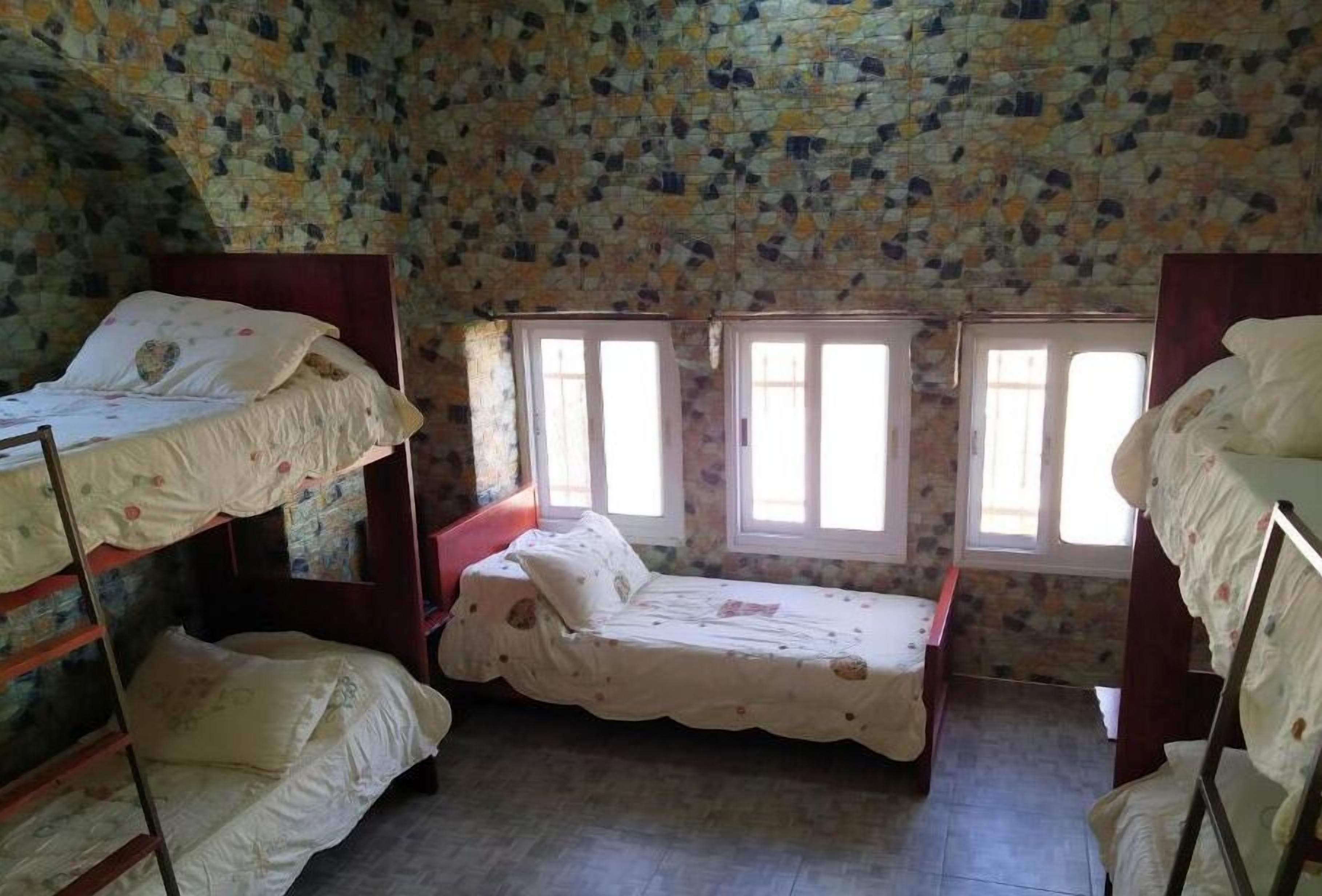 Una habitación con literas, una ventana con rejas y un techo con diseño de piedra.