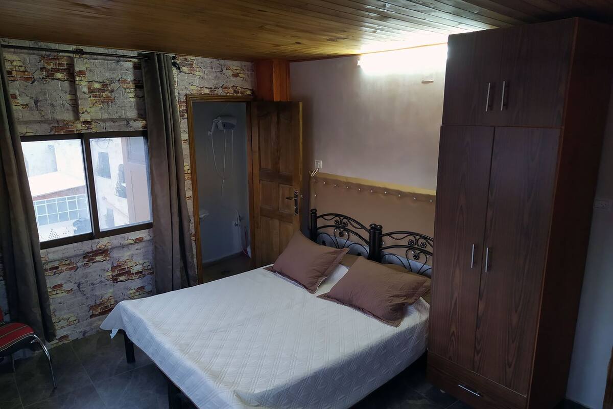 A bedroom with a bed, a wardrobe, and a window.