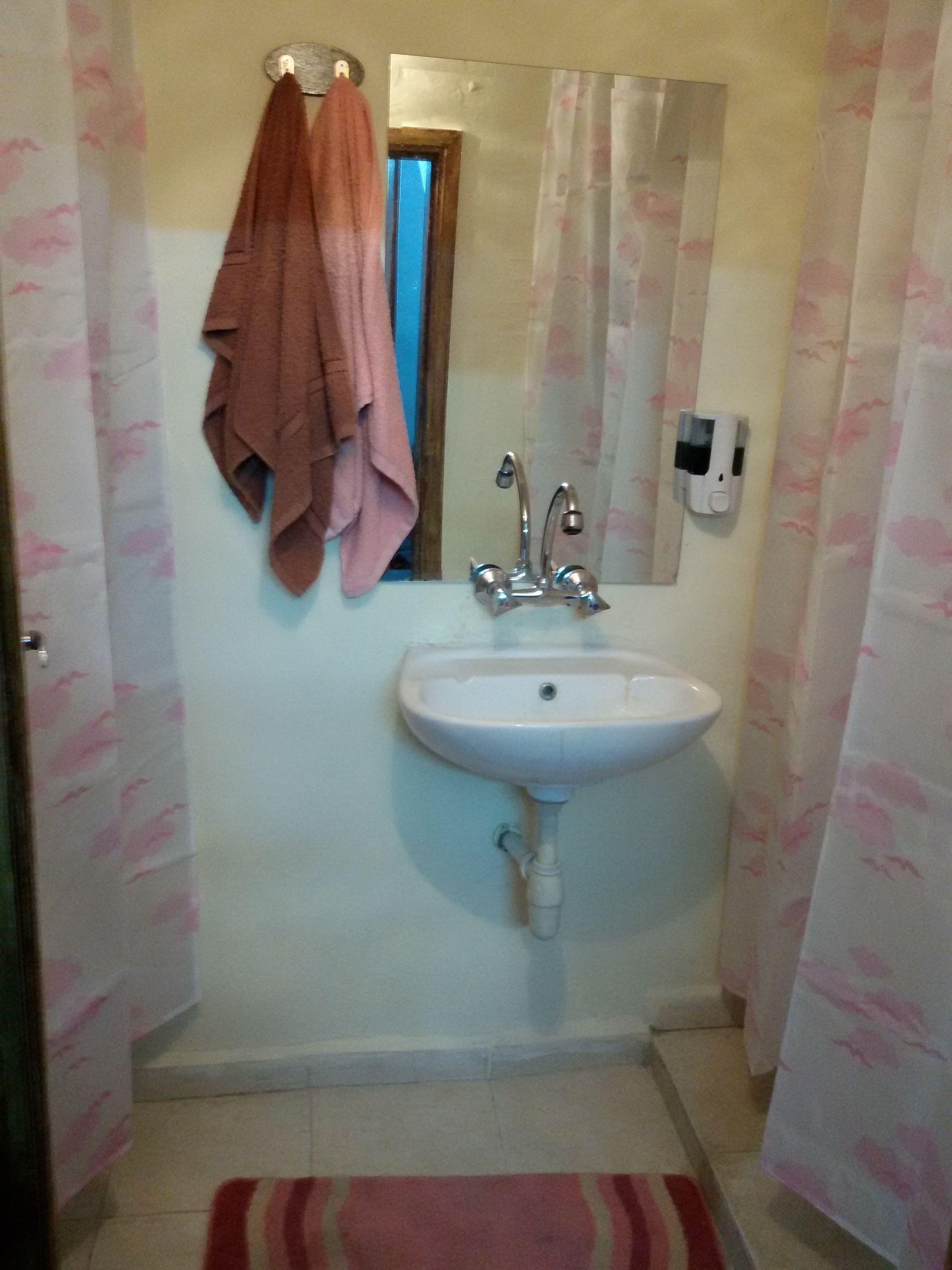 A bathroom with a sink, mirror, and towel rack.