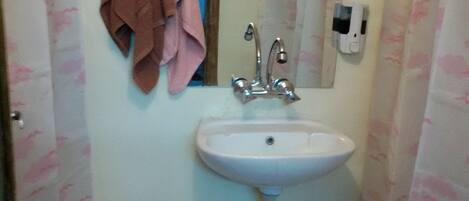 A bathroom with a sink, mirror, and towel rack.