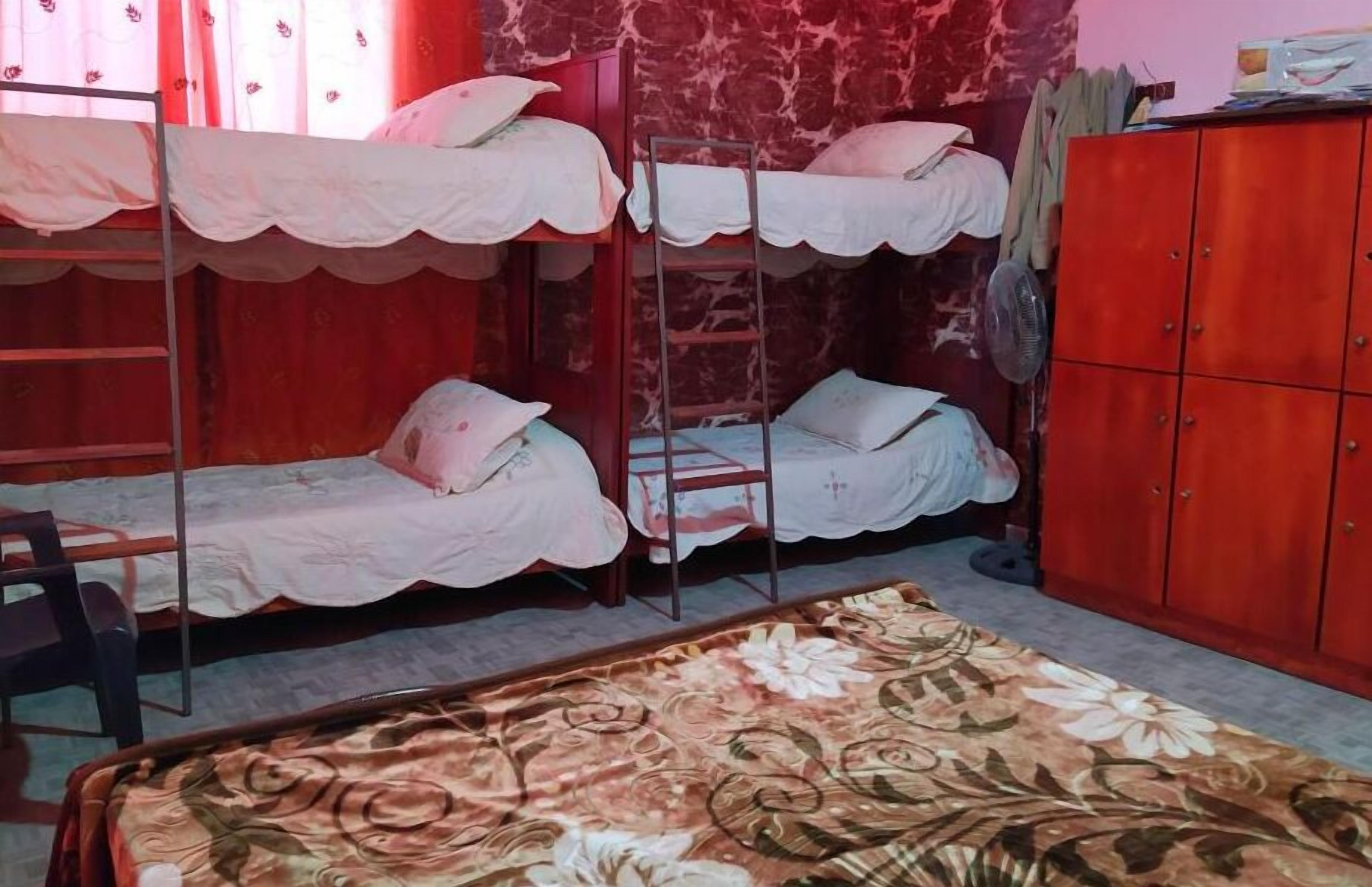 Habitación tipo dormitorio con literas, un armario de madera y una alfombra con motivos florales.